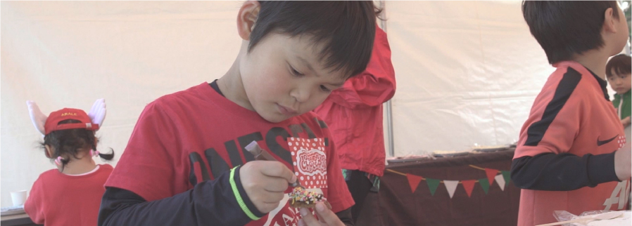 男の子が熱心にチョコレートでクッキーにデコレーション